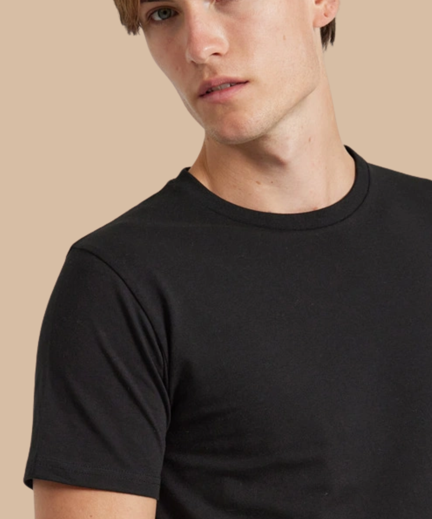 Man wearing a black t-shirt against a beige background. Standard stock for Pathfinder Printworks hand printing services. Based in South Wales.