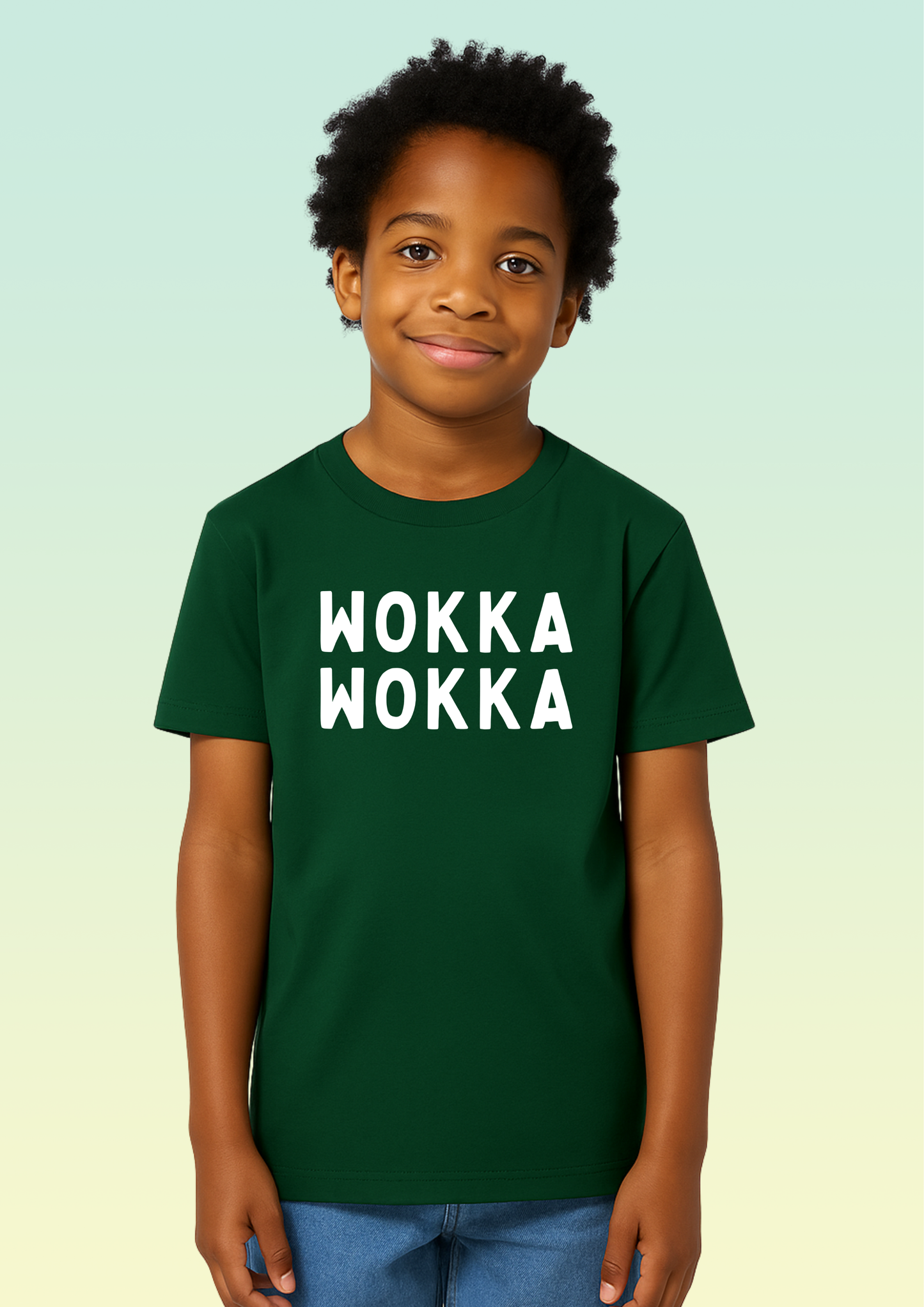 A young boy wearing a dark green crew neck t-shirt with the words 'WOKKA WOKKA' printed in bold white capital letters across the chest, set against a light green gradient background. Exclusive to Flying Teez.