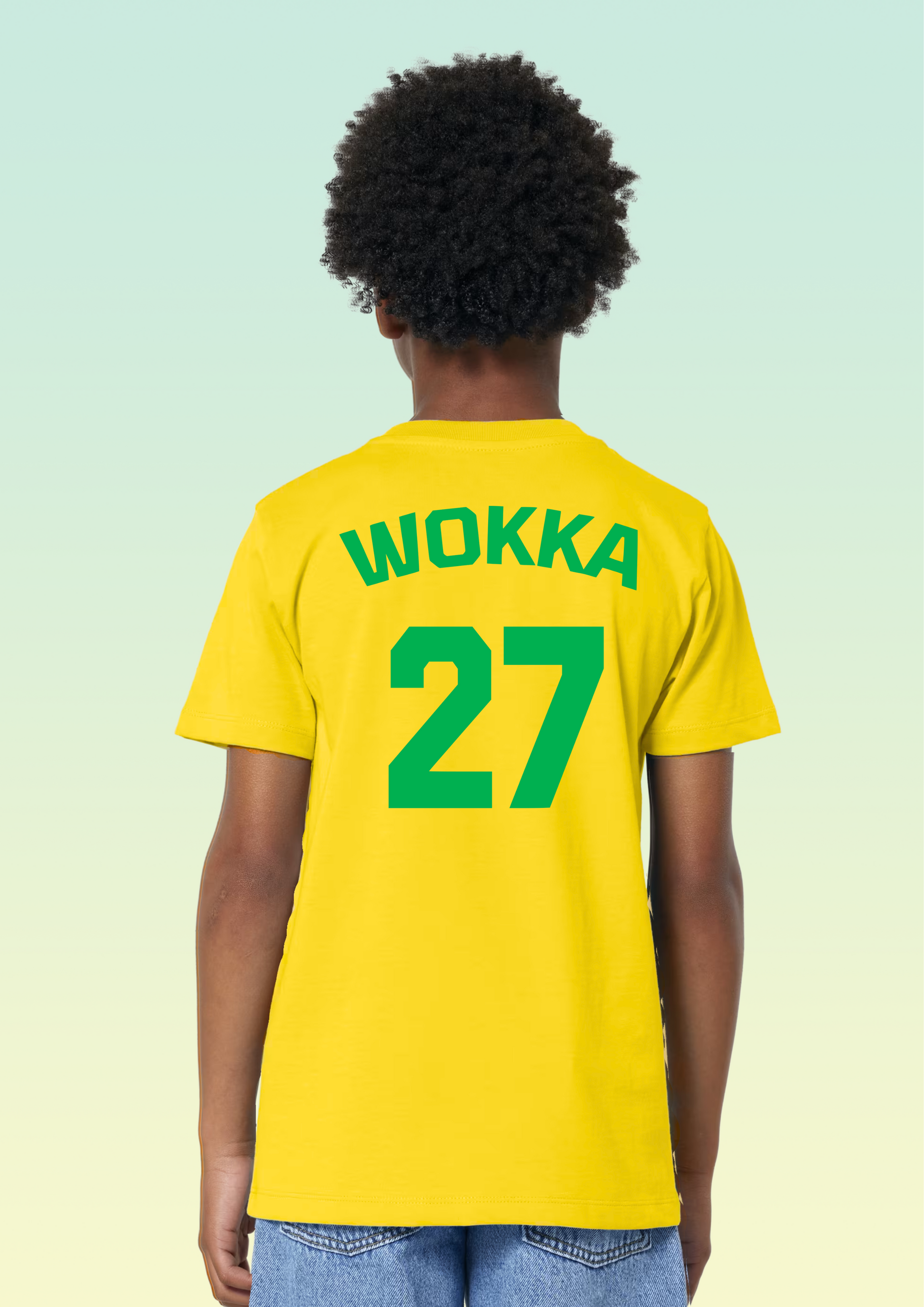 A child shown from the back wearing a bright yellow short-sleeve T-shirt with green text reading 'WOKKA' and the number '27' on the back, paired with blue jeans against a pale gradient background. Exclusive to Flying Teez.