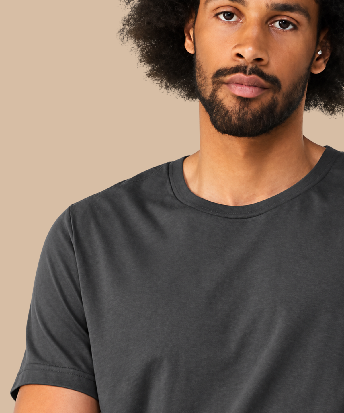 Man wearing a dark grey t-shirt against a beige background. Standard stock for Pathfinder Printworks hand printing services. Based in South Wales.