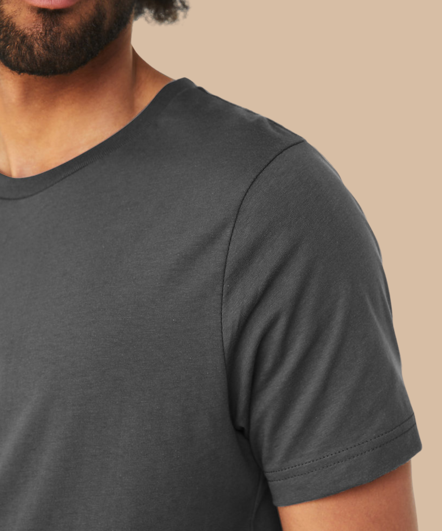 Man wearing a dark grey t-shirt against a beige background. Standard stock for Pathfinder Printworks hand printing services. Based in South Wales.