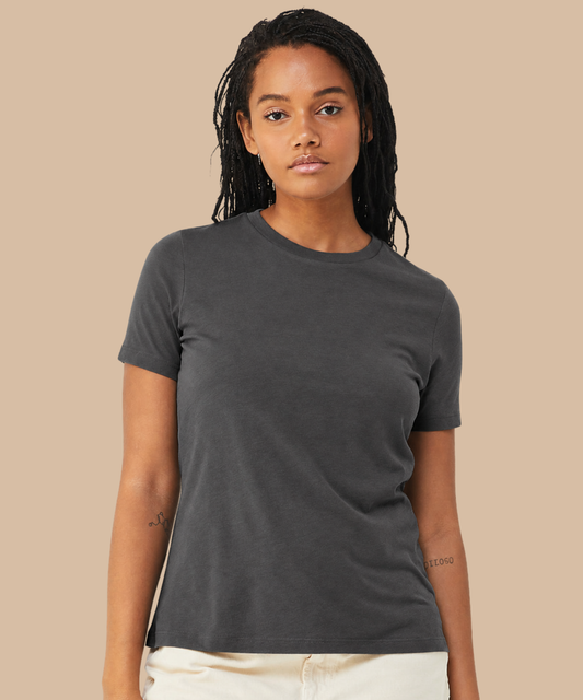 A woman modelling a dark charcoal grey short-sleeve crewneck t-shirt against a solid beige background. Standard stock for Pathfinder Printworks hand printing services. Based in South Wales.