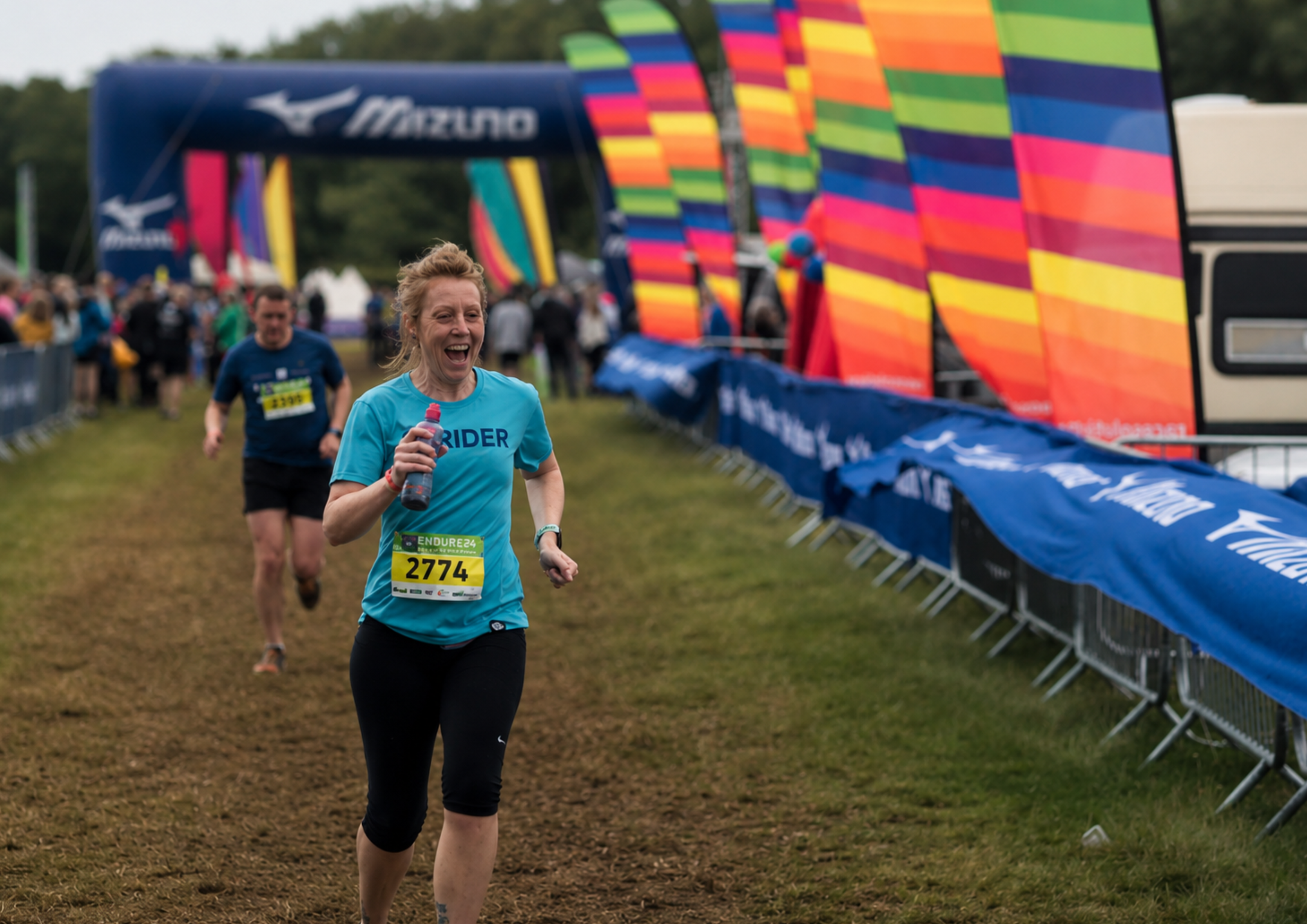 Woman joyfully running Endure 24 wearing a blue Strider t-shirt. Hand printed by Pathfinder Printworks in South Wales