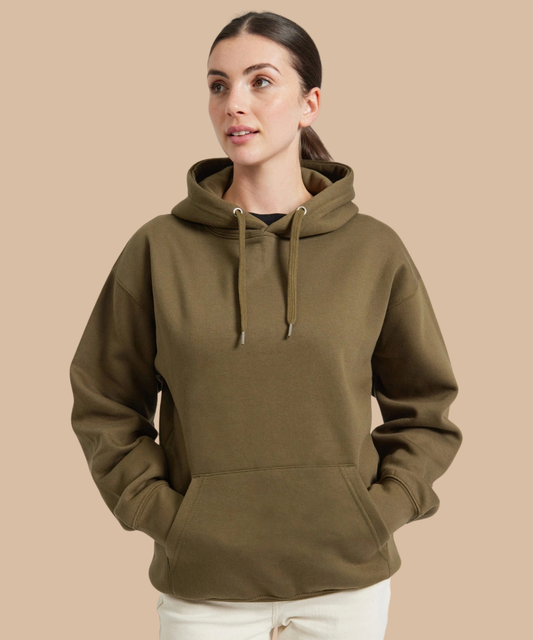 A woman wearing an olive green pullover hoodie with drawstrings and a kangaroo pocket, paired with white pants, set against a solid beige background. Pathfinder Printworks hand print for clubs, teams and businesses. 