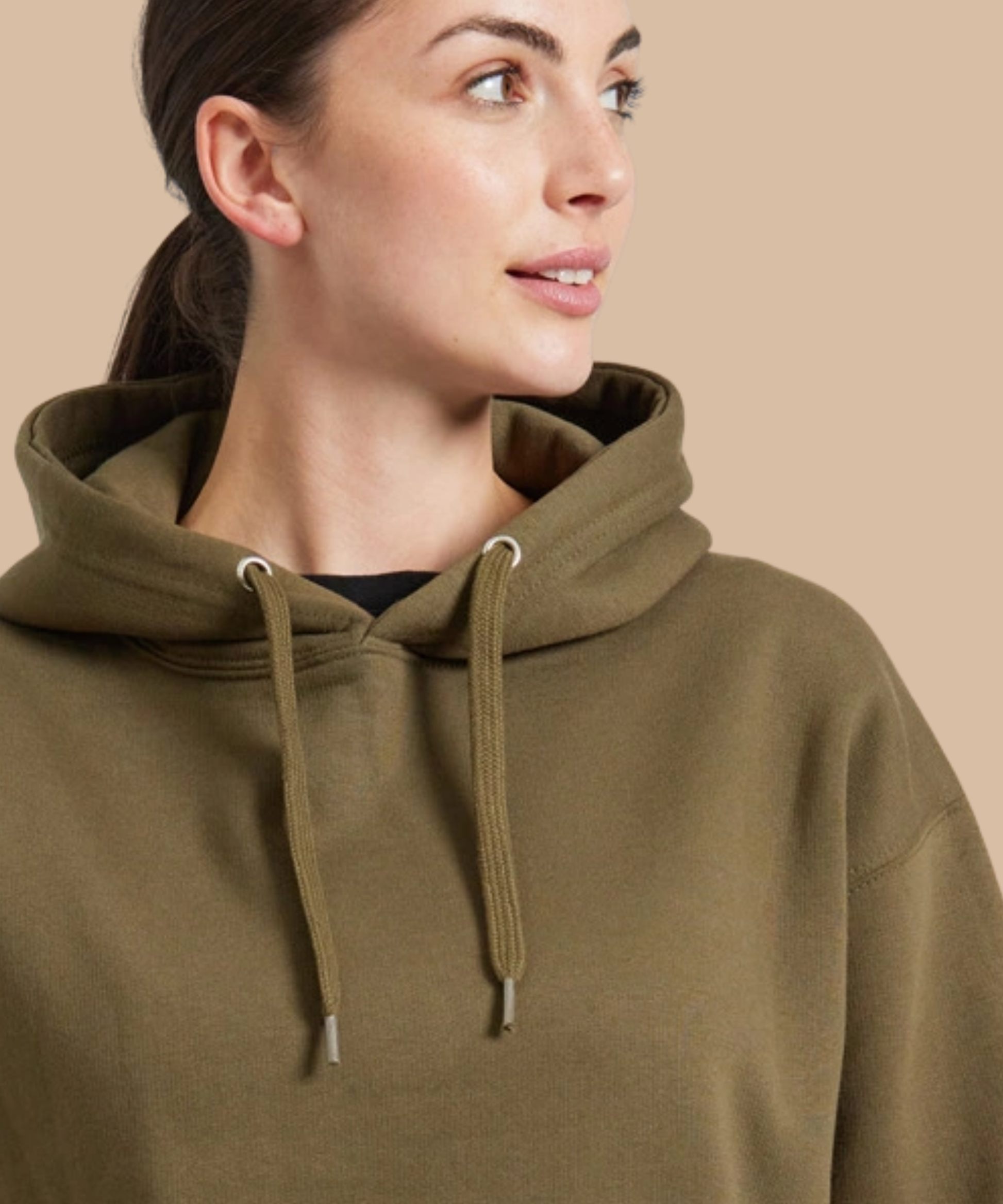 A close-up of a woman wearing an olive green pullover hoodie with matching drawstrings, set against a solid beige background. Pathfinder Printworks hand print for clubs, teams and businesses. 