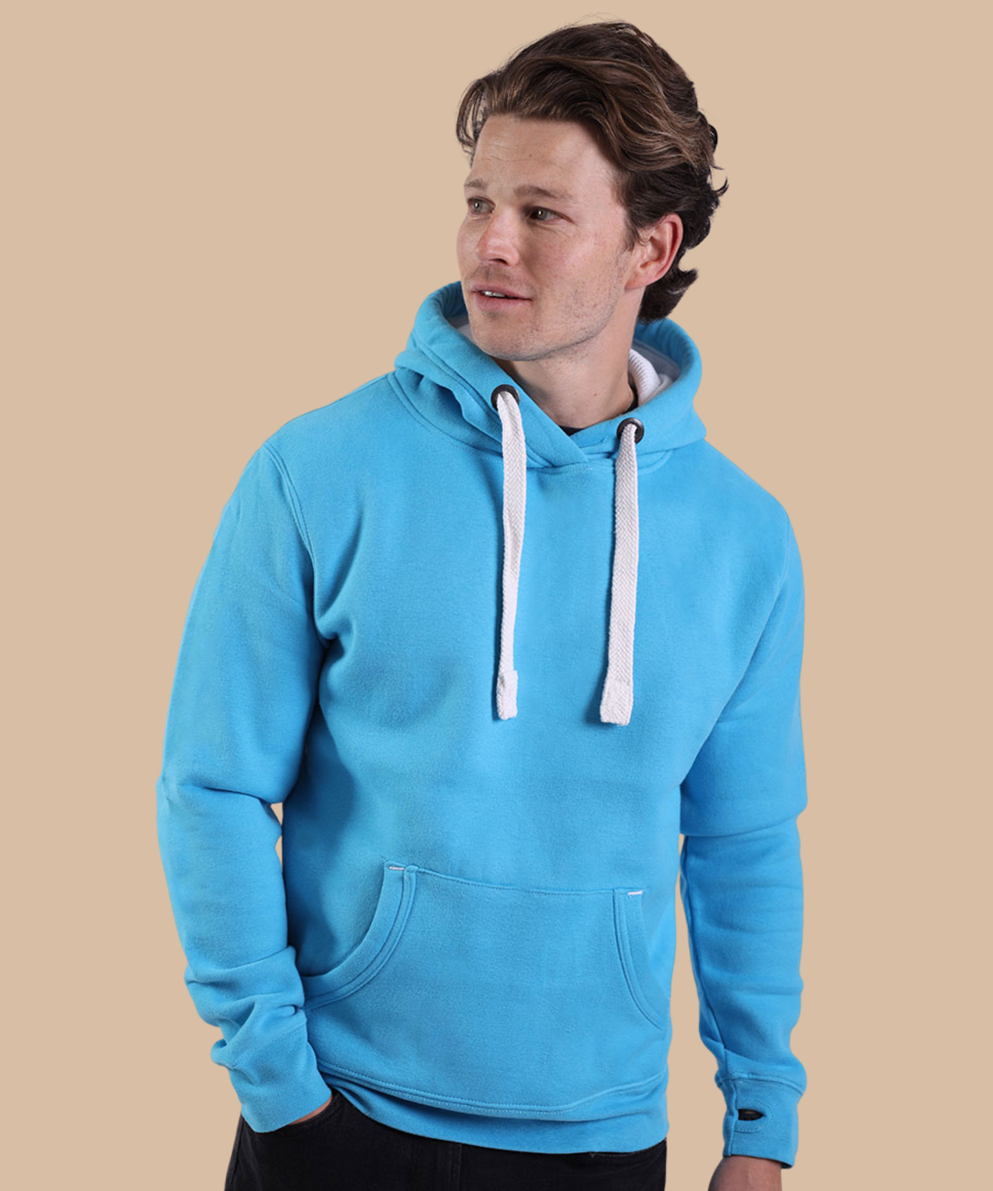 A man wearing a bright blue pullover hoodie with white drawstrings, standing against a solid beige background. Pathfinder Printworks hand print apparel for clubs, teams and businesses.