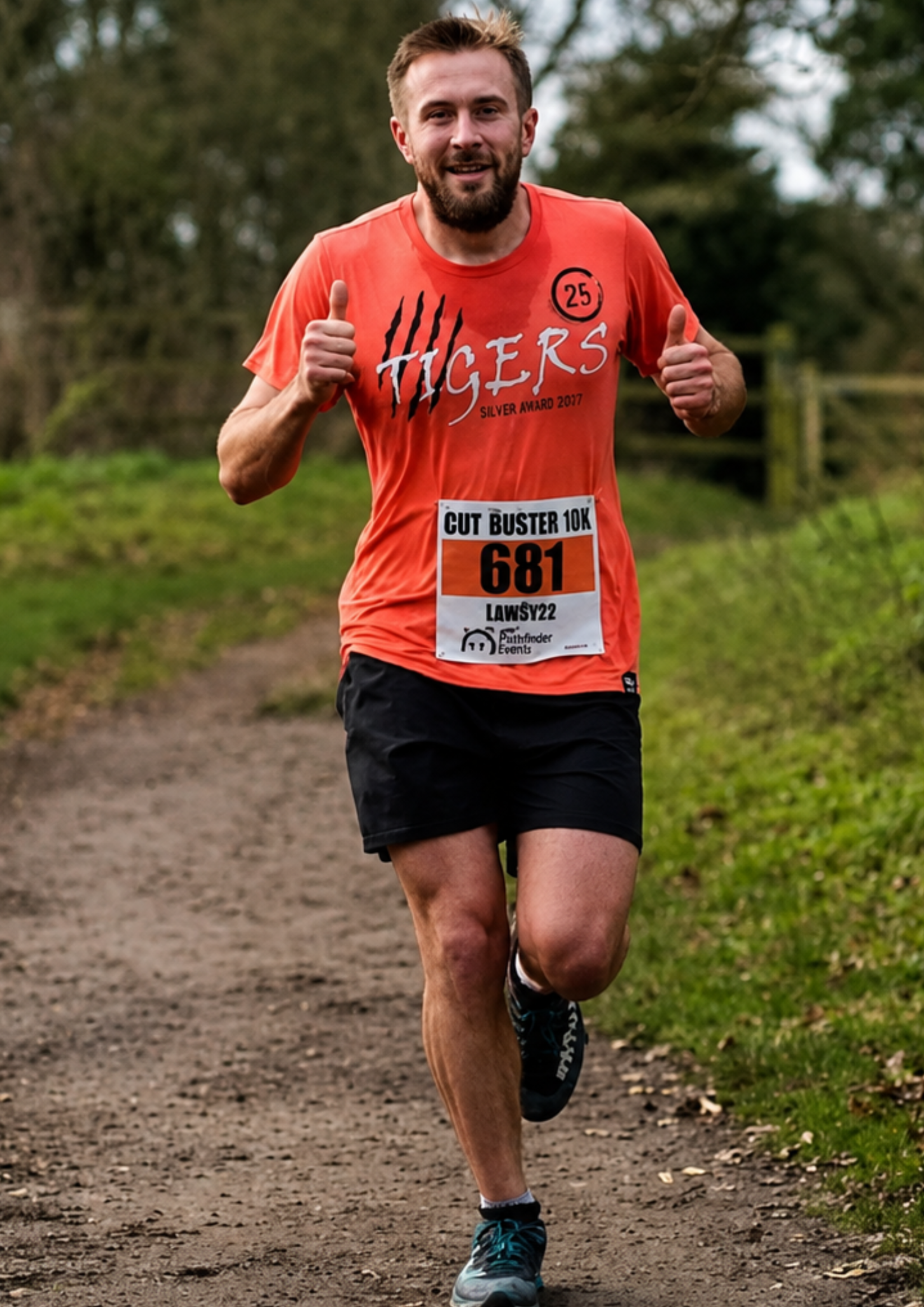 Man running outdoors on a dirt path wearing an orange t-shirt with 'Tigers' printed on it.