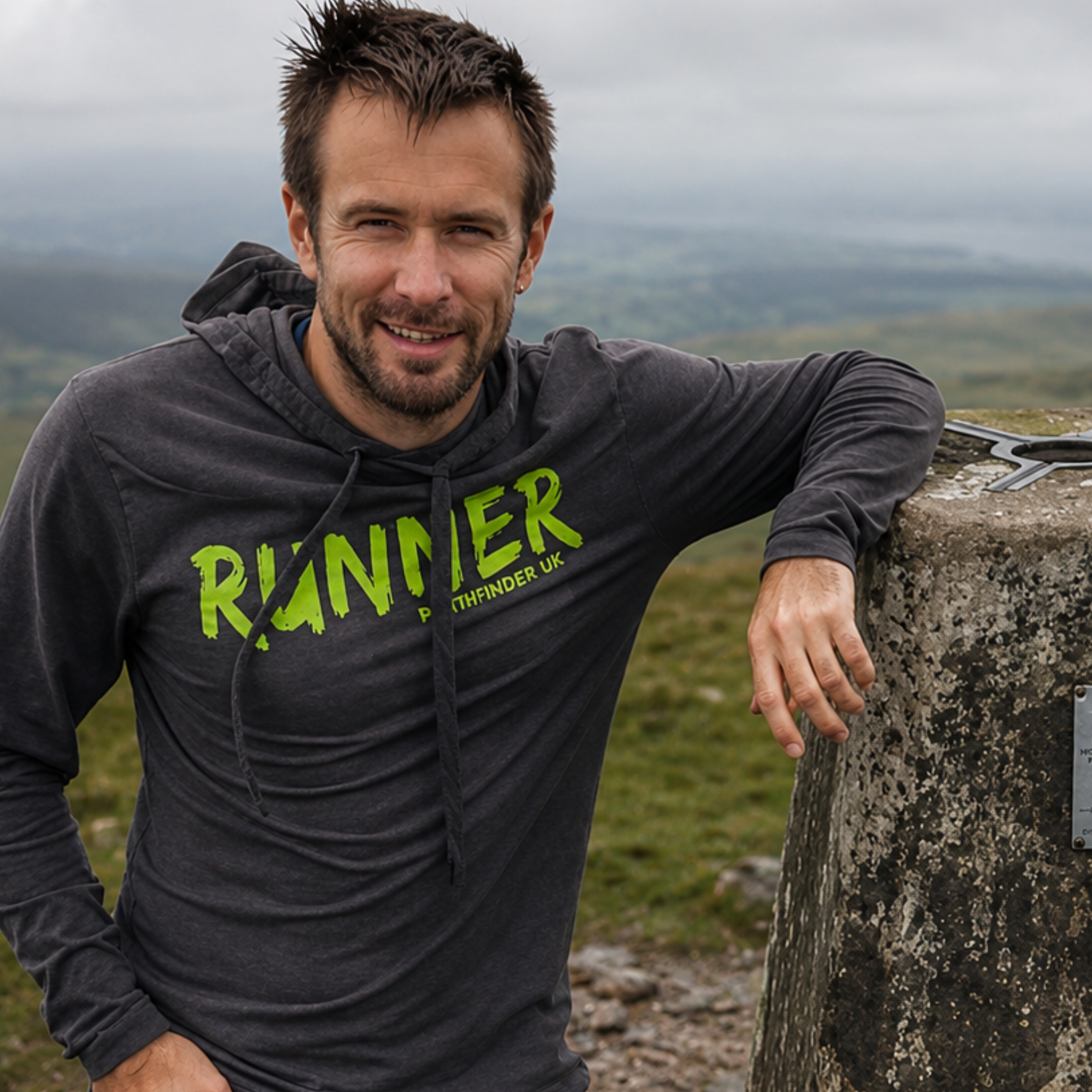 Smiling man wearing a grey top with RUNNER across the front in green. Showcasing Pathfinder UK and the online shop services via Pathfinder Printworks.