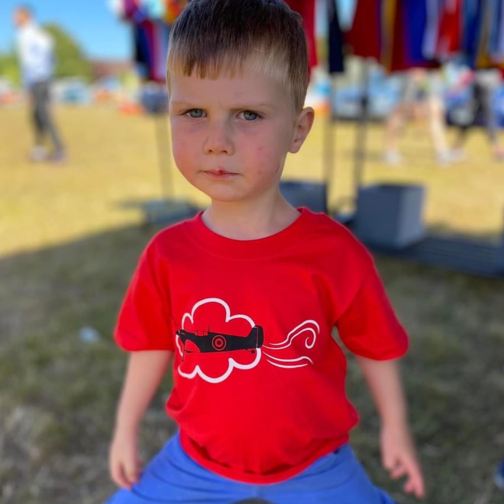 Young boy wearing a red t-shirt with a Spitfire airplane graphic printed on the front. The t-shirt is exclusively printed by Pathfinder Printworks for Flying Teez online shop.