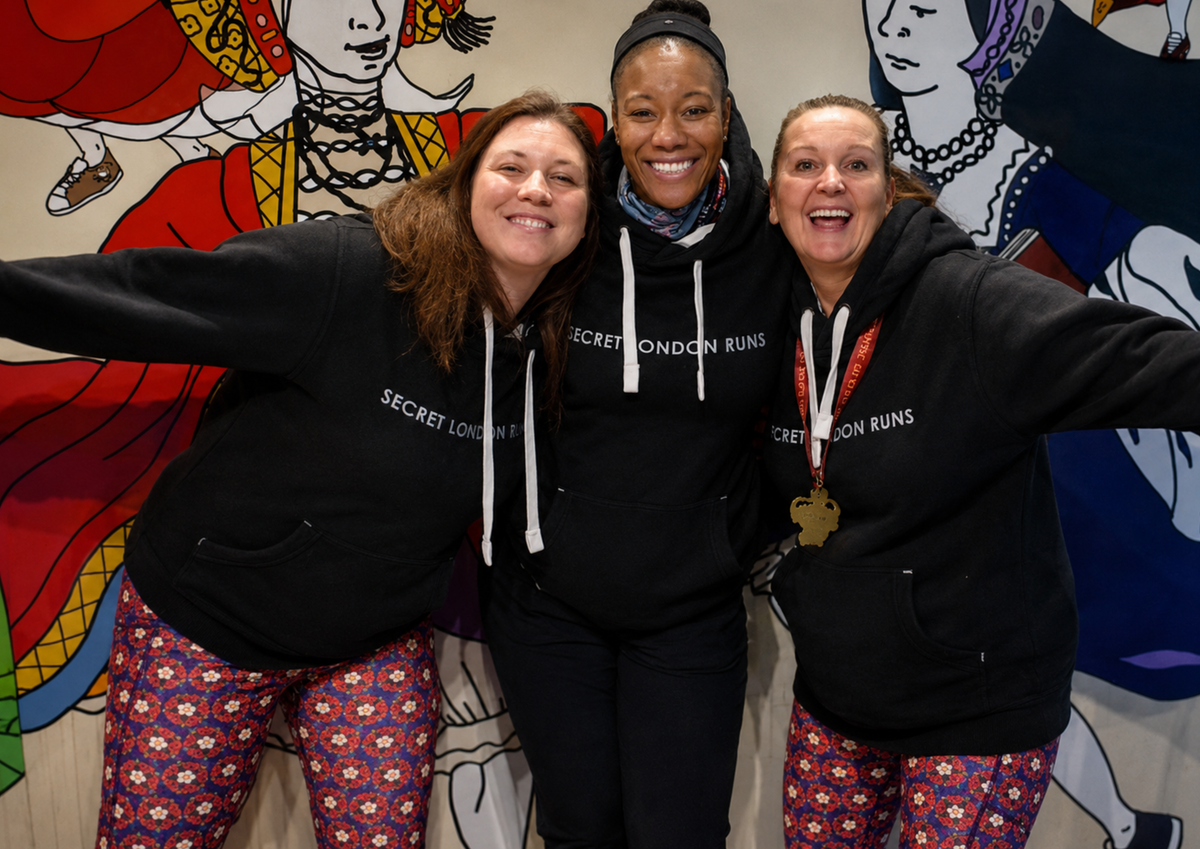 Three people wearing matching branded hoodies stand together smiling with their arms around one another. The image highlights team identity, belonging and the sense of community created through shared apparel.