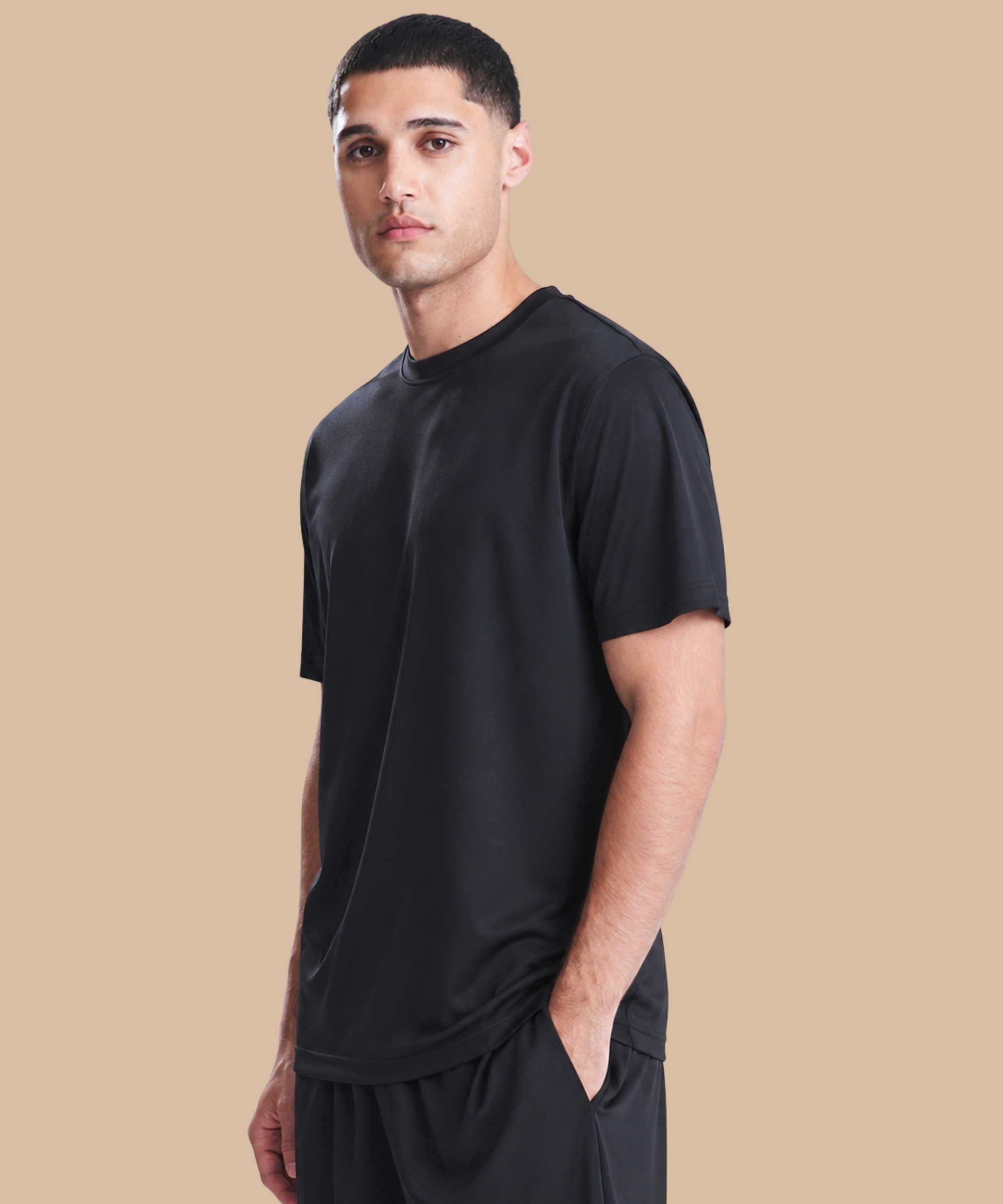 Man wearing a black t-shirt and pants on a beige background. Standard stock for Pathfinder Printworks hand printing services. Based in South Wales.