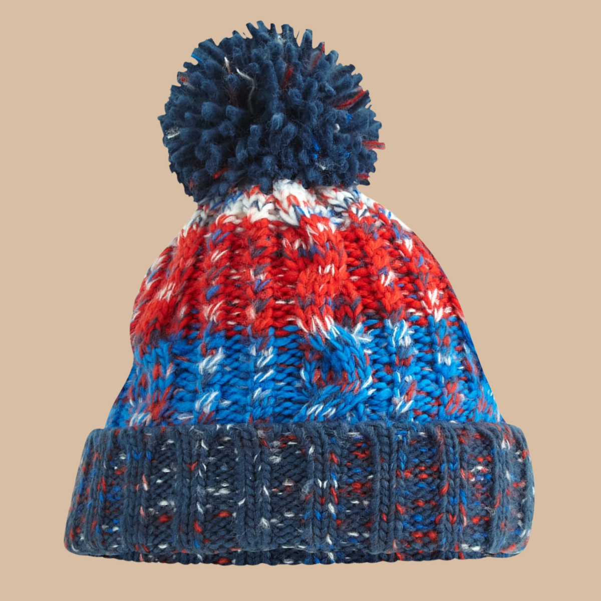 A chunky knit pom-pom beanie hat featuring a marled pattern of navy blue, red, and white yarn, with a solid navy ribbed cuff and matching pom-pom, shown against a solid beige background. Embroidery services from Pathfinder Printworks, based in South Wales.