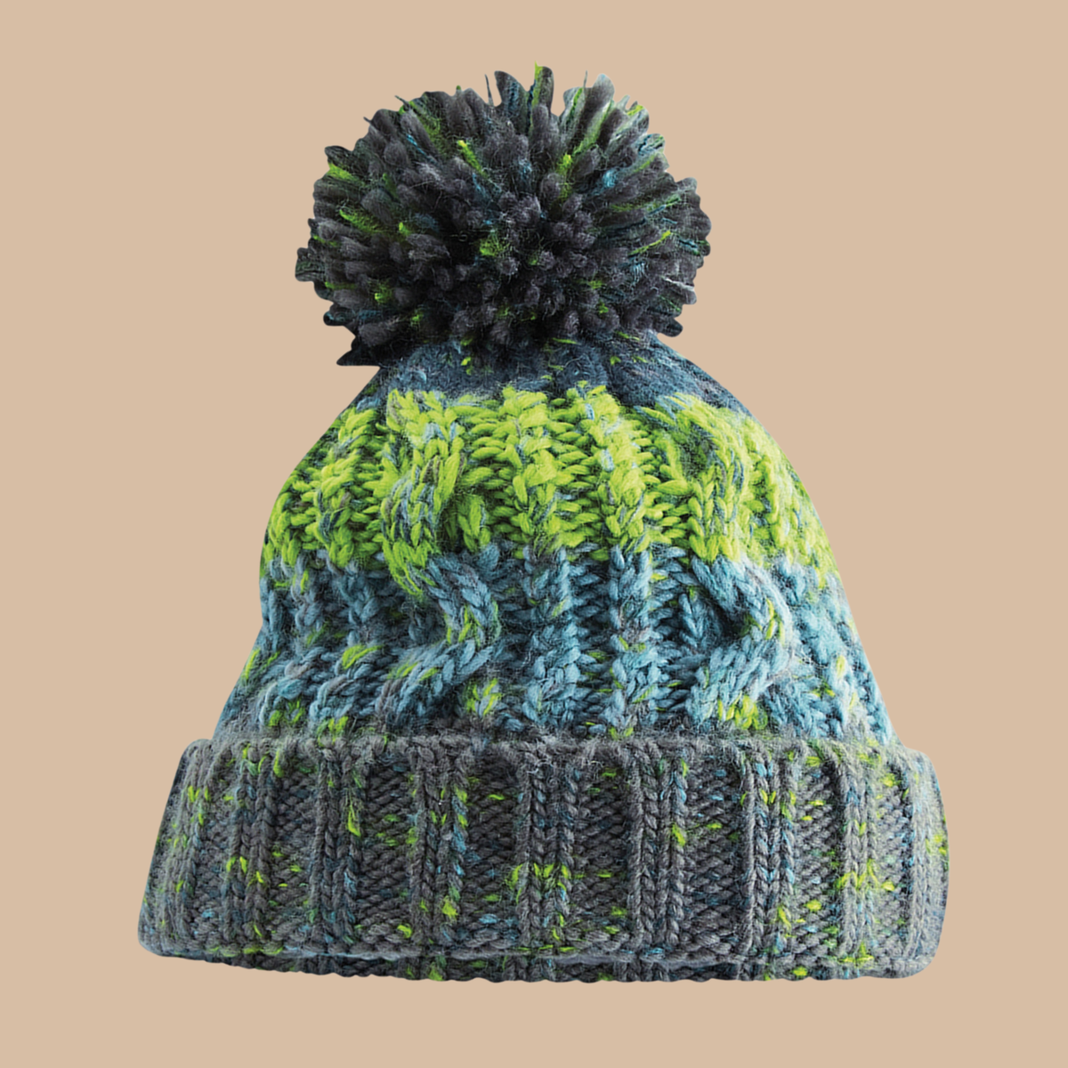 A chunky knit pom-pom beanie hat featuring a variegated pattern of blue, grey, and neon green yarn, set against a solid beige background. Embroidery services from Pathfinder Printworks, based in South Wales.