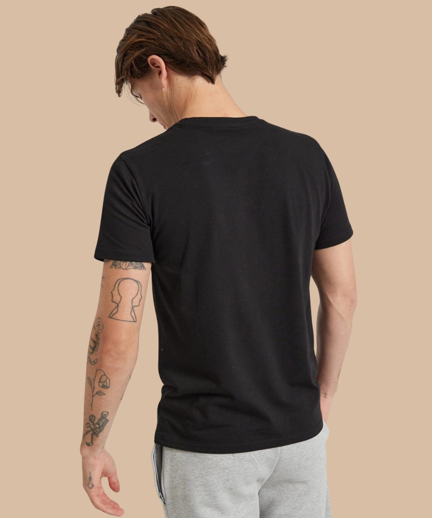 Man wearing a black t-shirt on a beige background. Standard stock for Pathfinder Printworks hand printing services. Based in South Wales.