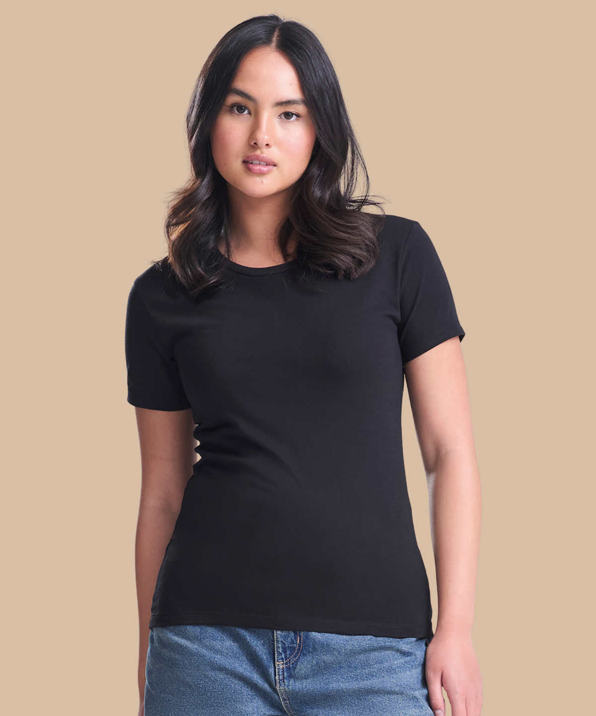 A woman modelling a black short-sleeve crewneck t-shirt against a solid beige background. Standard stock for Pathfinder Printworks hand printing services. Based in South Wales.