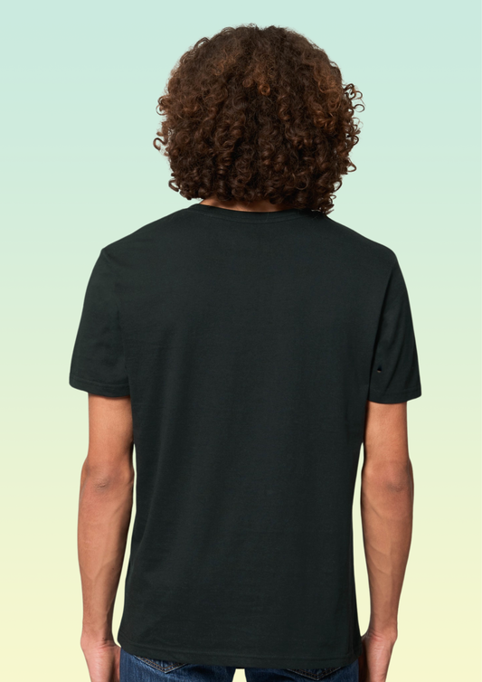A person viewed from the back wearing a plain black short-sleeve T-shirt, with curly brown hair and blue jeans, against a pale mint-to-yellow gradient background. Exclusive to Flying Teez.