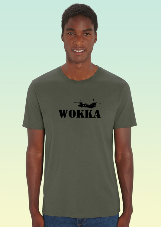 A man wearing an olive green crewneck t-shirt with a black graphic of a helicopter and the word 'WOKKA' printed on the chest, set against a light green gradient background. Exclusive to Flying Teez.