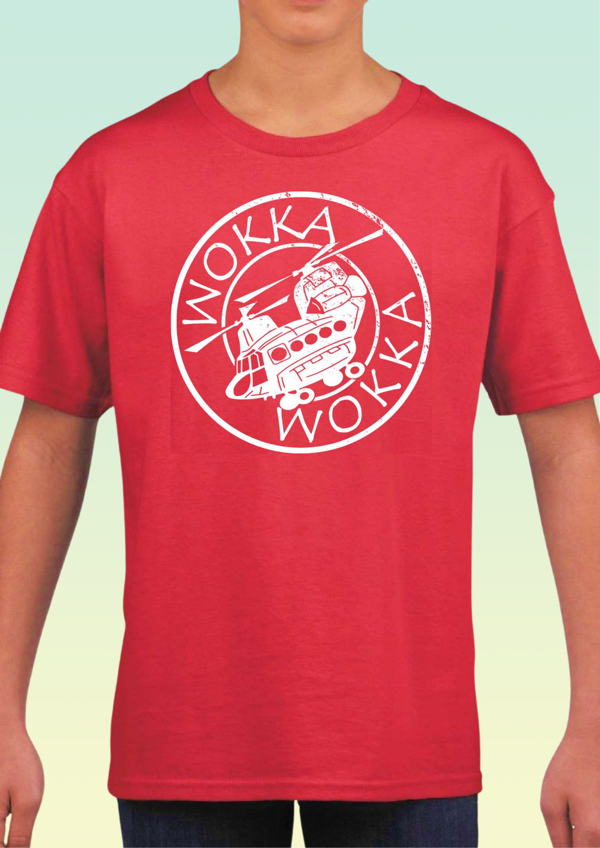 A red short-sleeve crewneck t-shirt with a white distressed circular graphic on the chest featuring a helicopter and the word 'WOKKA' repeated, shown on a model against a pale green gradient background. Exclusive to Flying Teez.