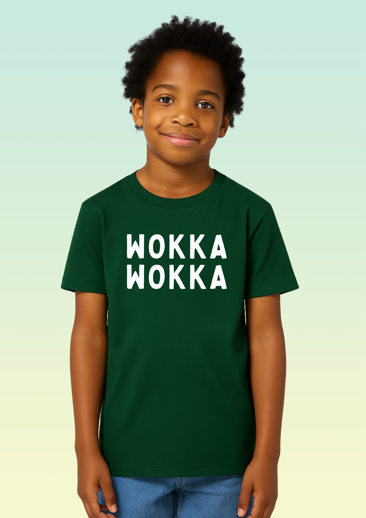 A young boy wearing a dark green crew neck t-shirt with the words 'WOKKA WOKKA' printed in bold white capital letters across the chest, set against a light green gradient background. Exclusive to Flying Teez.